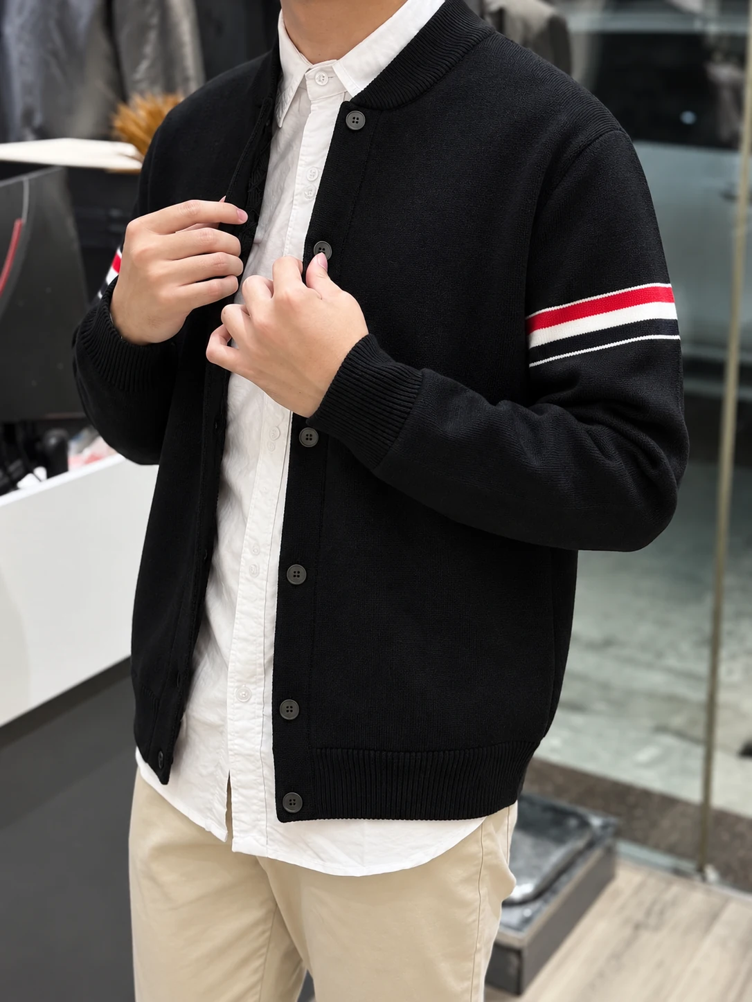 Cardigan đen với đường kẻ đỏ trắng trên tay áo, phối cùng sơ mi trắng